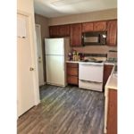 Kitchen with wood style flooring, white appliances, and wooden cabinets.