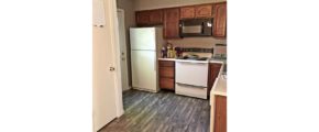 Kitchen with wood style flooring, white appliances, and wooden cabinets.