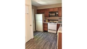 Kitchen with wood style flooring, white appliances, and wooden cabinets.