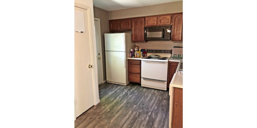 Kitchen with wood style flooring, white appliances, and wooden cabinets.