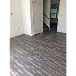 Unfurnished living room with gray, wood-style flooring and carpeted stairs to the second floor.