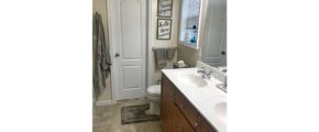 Bathroom with vanity with dual sinks, toilet, and tile-style flooring