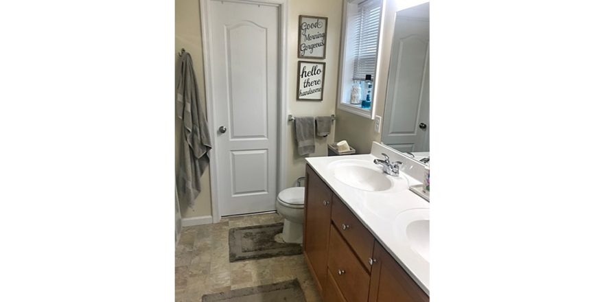 Bathroom with vanity with dual sinks, toilet, and tile-style flooring