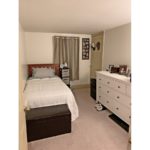 Bedroom with twin bed, dresser, window and storage ottoman