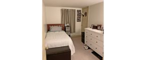 Bedroom with twin bed, dresser, window and storage ottoman