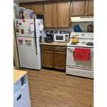 Kitchen with white appliances, wood-style flooring and wood cabinets