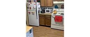 Kitchen with white appliances, wood-style flooring and wood cabinets