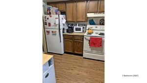 Kitchen with white appliances, wood-style flooring and wood cabinets