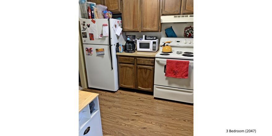 Kitchen with white appliances, wood-style flooring and wood cabinets