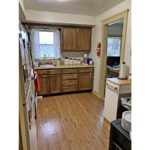 Kitchen with white appliances, wood-style flooring and wood cabinets