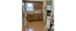 Kitchen with white appliances, wood-style flooring and wood cabinets