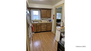 Kitchen with white appliances, wood-style flooring and wood cabinets