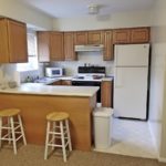 Kitchen with white appliances, wood-tone cabinets, and barstool seating