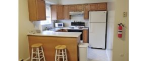 Kitchen with white appliances, wood-tone cabinets, and barstool seating