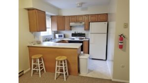 Kitchen with white appliances, wood-tone cabinets, and barstool seating