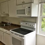 Kitchen with white cabinets, sink and white appliances