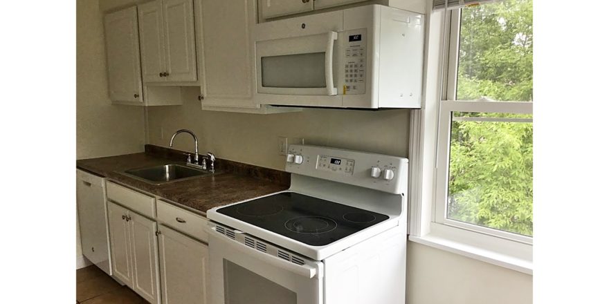 Kitchen with white cabinets, sink and white appliances