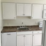 Kitchen with white cabinets, sink and white appliances