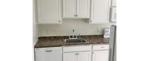 Kitchen with white cabinets, sink and white appliances