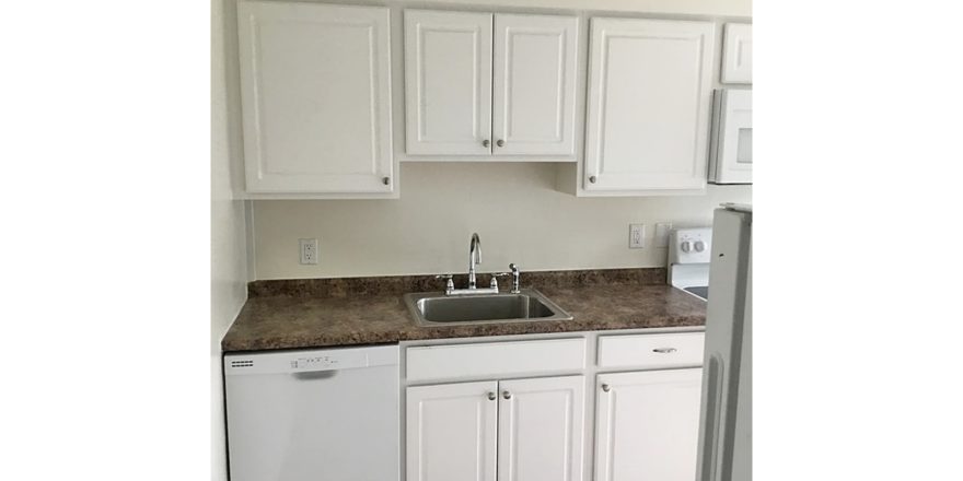 Kitchen with white cabinets, sink and white appliances