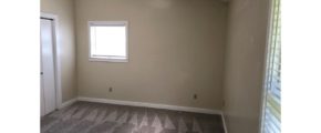 Carpeted, unfurnished bedroom with two windows and closet