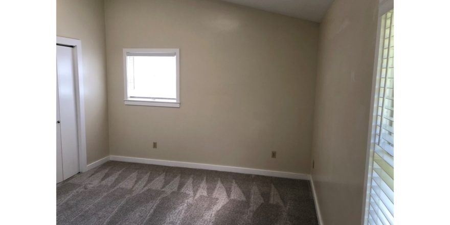 Carpeted, unfurnished bedroom with two windows and closet