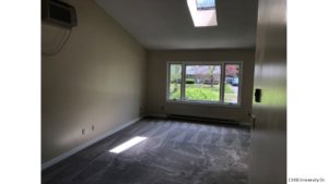Carpeted, unfurnished, combined living and dining room with large picture window and skylight