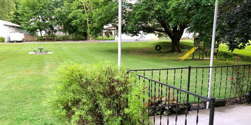 Large yard with bench, tire swing, and small play fort