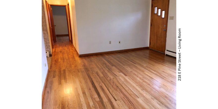 Unfurnished living room with hardwood floor and entry door