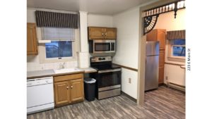 Kitchen with light wood cabinets, stainless steel and white appliances, and tile backsplash