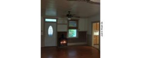 Living room with wood-burning fireplace, exposed brick, exposed beam, and hardwood floors