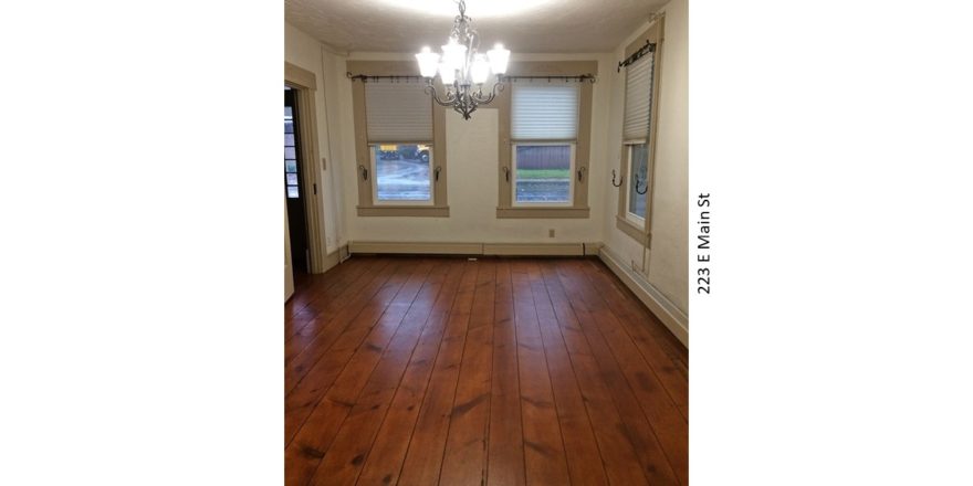 Unfurnished dining room with windows, chandelier, and hardwood floors