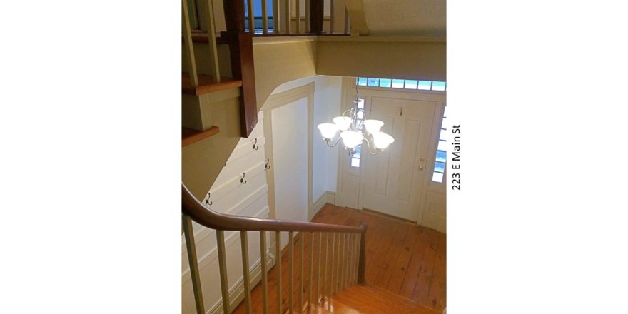 Entryway with wooden staircase, wood floors, and chandelier