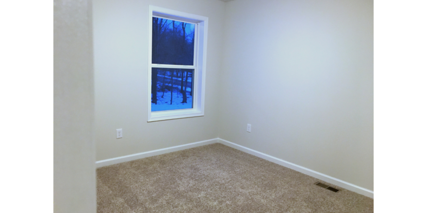 Unfurnished bedroom with tan carpet.