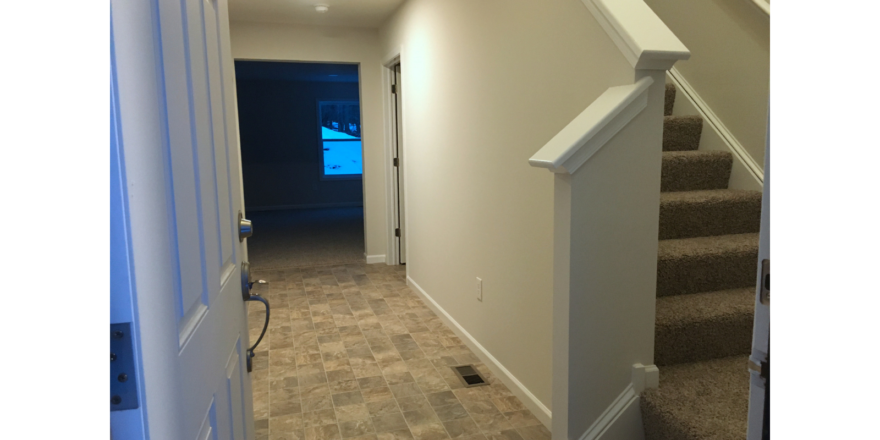 Entry way with tile-style laminate floor and carpeted stairs to the second floor.