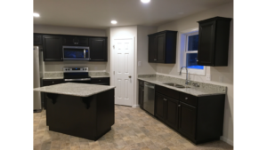 Corner kitchen with stone counter tops, black cabinets, and stainless steel appliances