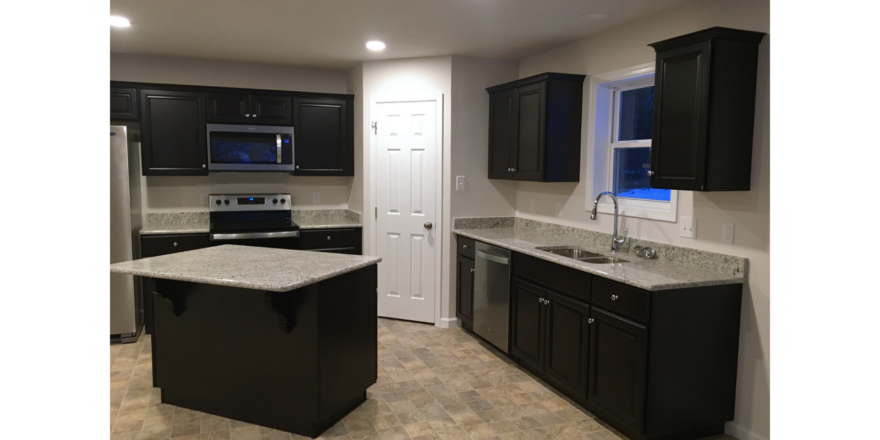 Corner kitchen with stone counter tops, black cabinets, and stainless steel appliances