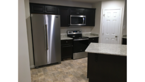 Kitchen with stainless steel appliances, black cabinets, and stone counter tops