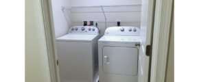 Laundry close with side-by-side top load washer and front load dryer with a white wire shelf above.