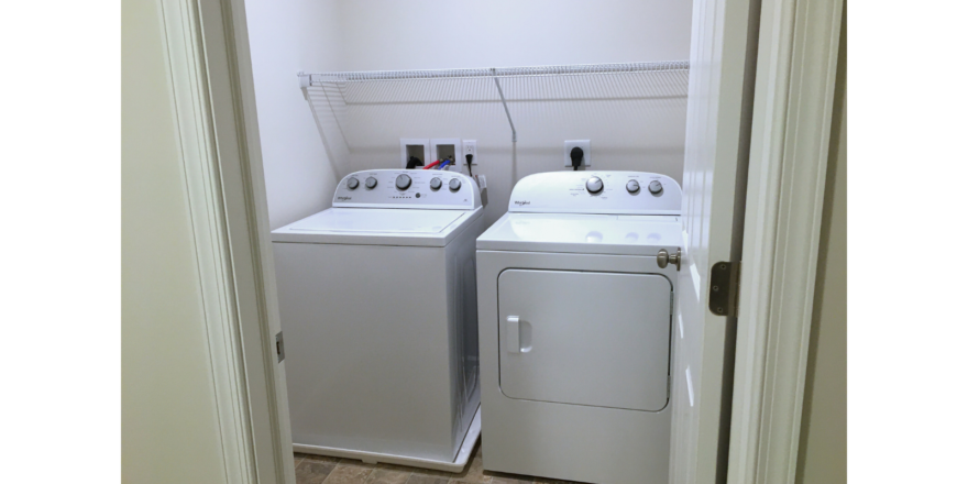 Laundry close with side-by-side top load washer and front load dryer with a white wire shelf above.