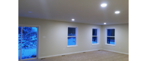 Unfurnished, carpeted living room with three windows and a sliding glass door.