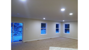 Unfurnished, carpeted living room with three windows and a sliding glass door.