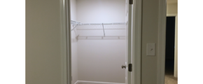 Walk in closet with white wire shelving and clothes rods