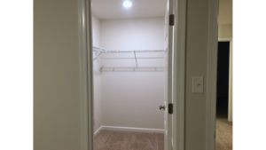 Walk in closet with white wire shelving and clothes rods