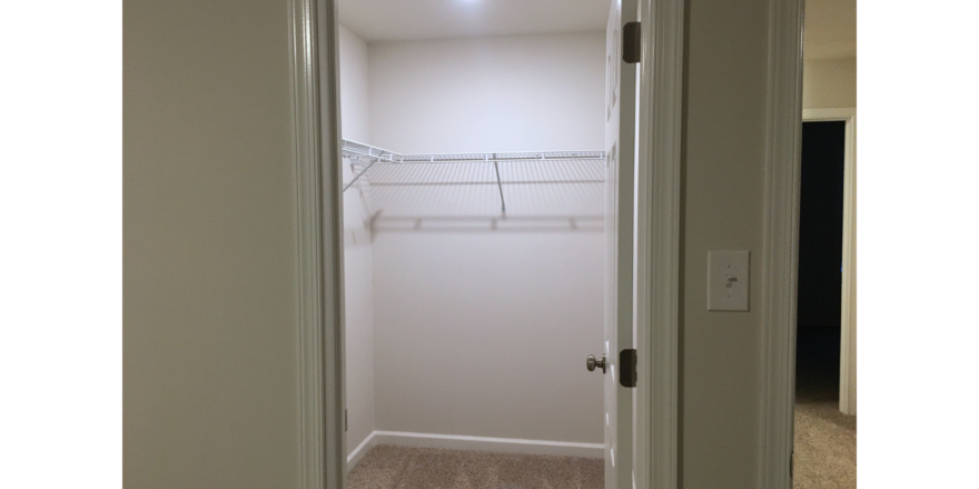 Walk in closet with white wire shelving and clothes rods