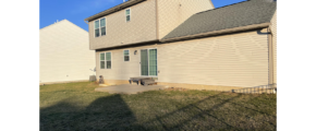 the back of a house with a bench in the yard