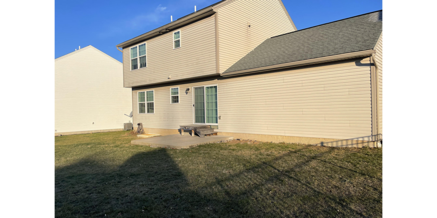 the back of a house with a bench in the yard