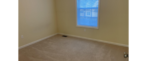 an empty room with a window and carpet