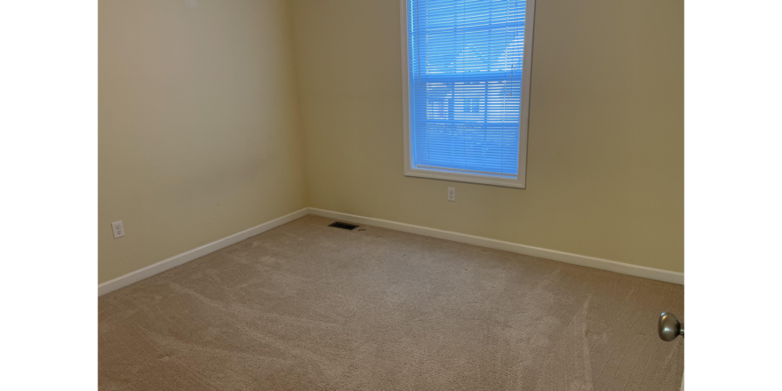 an empty room with a window and carpet