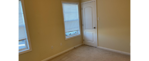 an empty room with two windows and a door